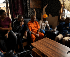 Five community stakeholders seated during a meeting and discussion in an indoor setting in Nigeria.