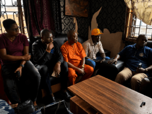 Five community stakeholders seated during a meeting and discussion in an indoor setting in Nigeria.