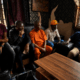 Five community stakeholders seated during a meeting and discussion in an indoor setting in Nigeria.