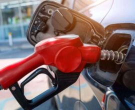 Petrol attendant dispensing fuel while a motorist checks the pump reading