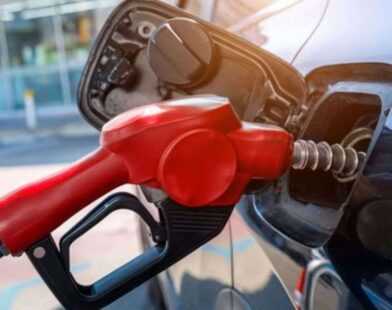 Petrol attendant dispensing fuel while a motorist checks the pump reading