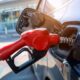 Petrol attendant dispensing fuel while a motorist checks the pump reading